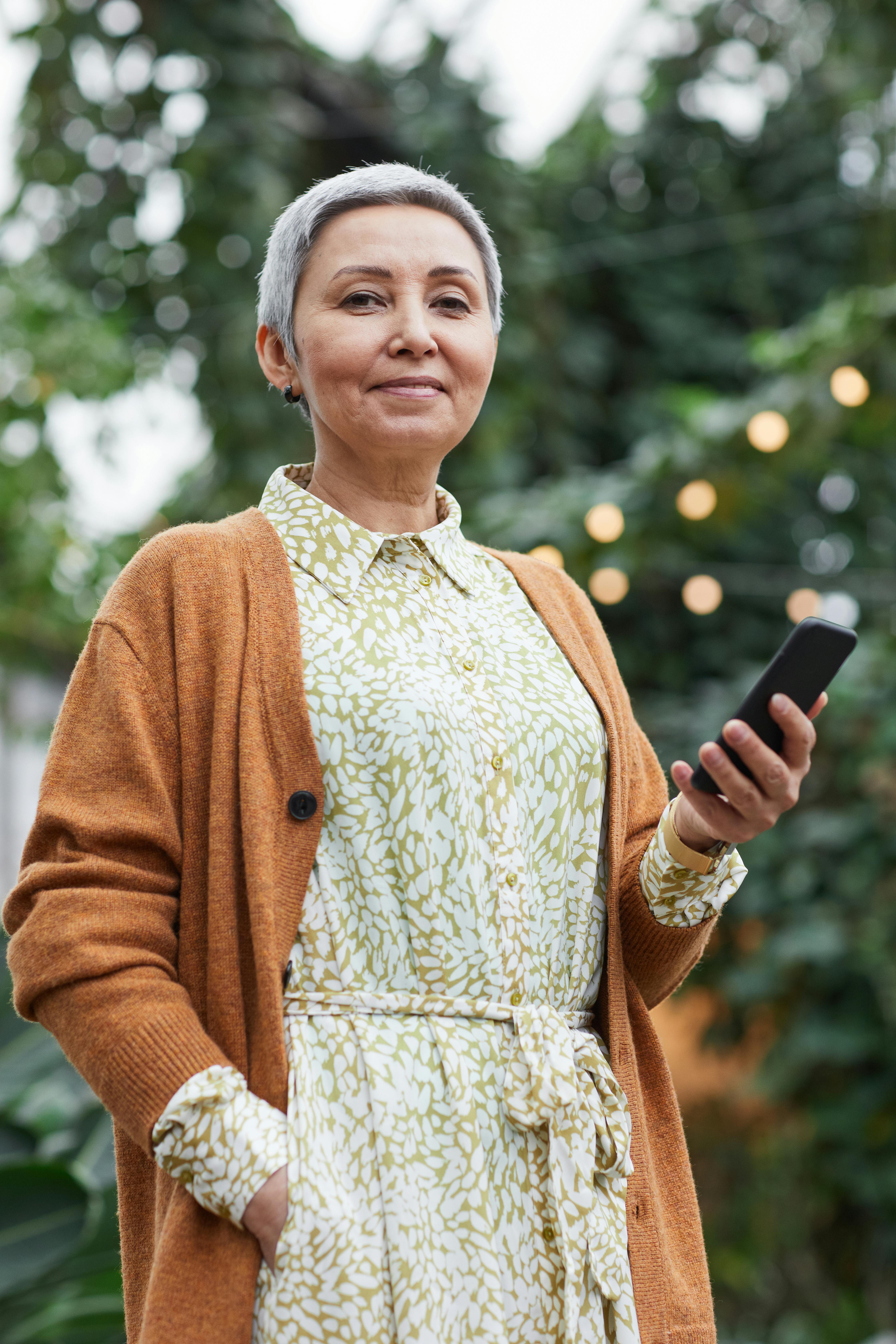 woman holding her smartphone while smiling at the camera