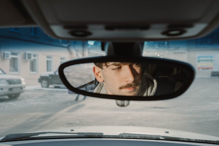 A Man's Reflection On A Rear View Mirror