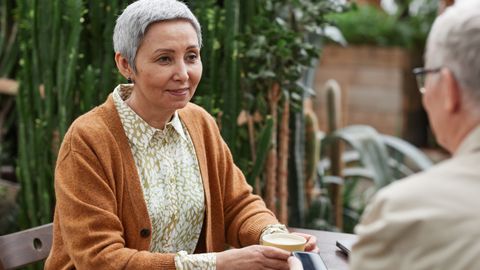 A senior couple enjoying coffee and conversation in a lush garden setting