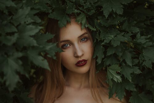 Dreamy young lady standing under tree branches