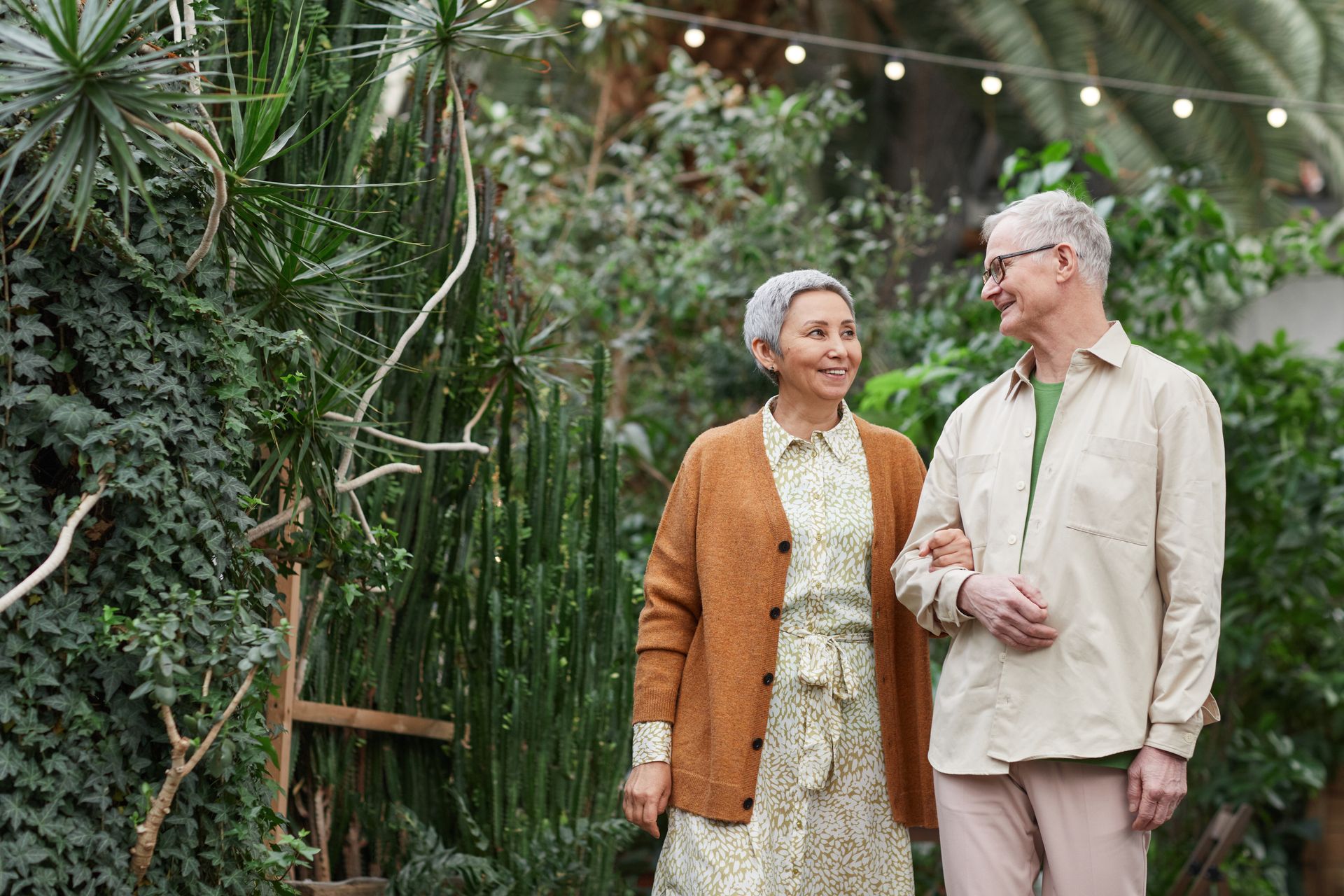 Elderly couple walking arm in arm in a garden