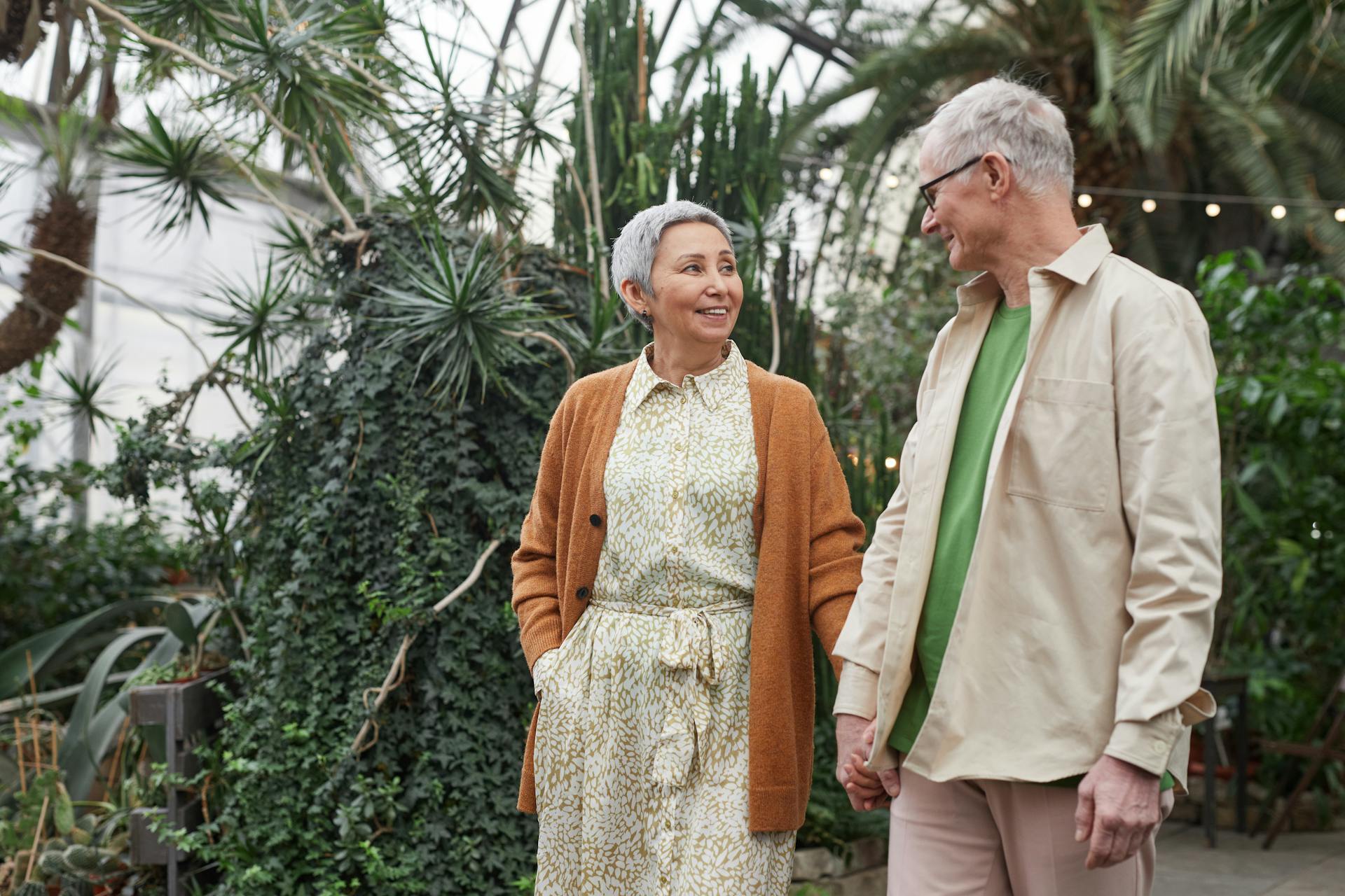 Senior couple enjoying a date in a lush botanical garden, sharing smiles and holding hands.