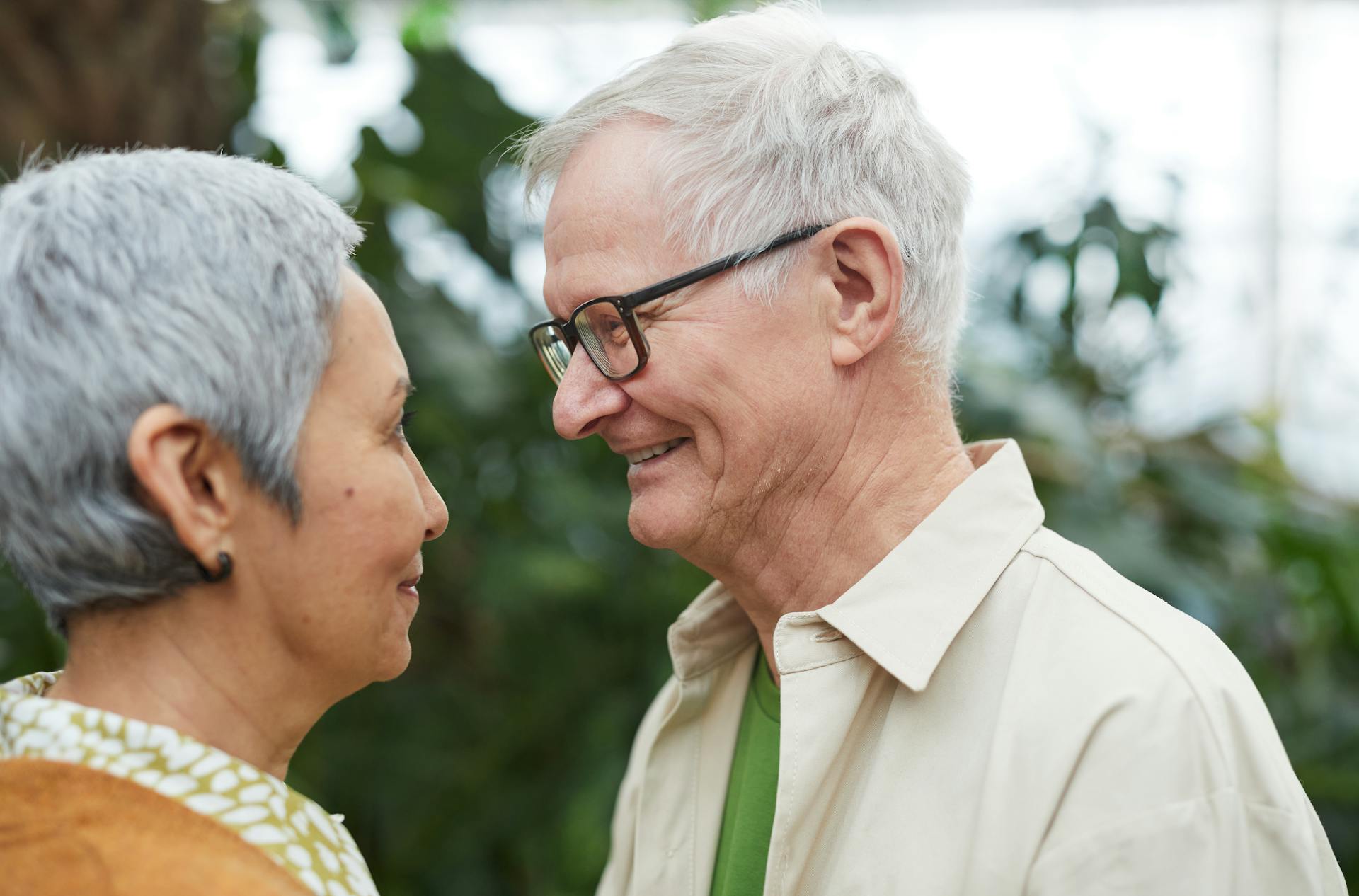 Loving senior couple smiling at each other in a peaceful garden environment.