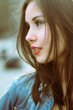 Stunning profile portrait of a young woman with long brown hair in a denim jacket.