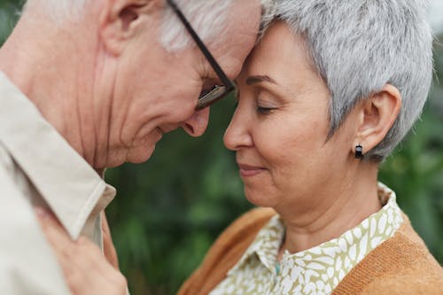 A tender moment between a senior couple, expressing love and affection outdoors.