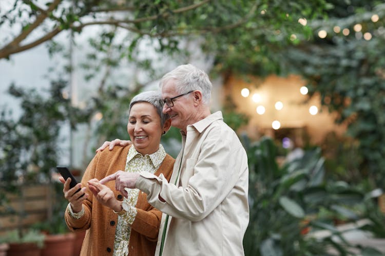 Couple Smiling While Looking At A Smartphone