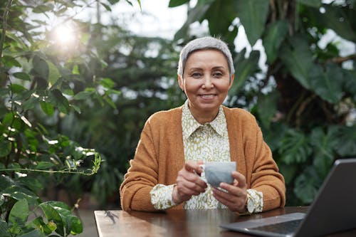 Woman Smiling While Holding a Coffee Cup