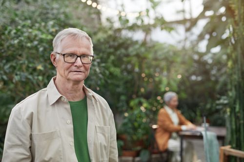 Free Elderly man with glasses in a lush greenhouse environment, focused and serene. Stock Photo
