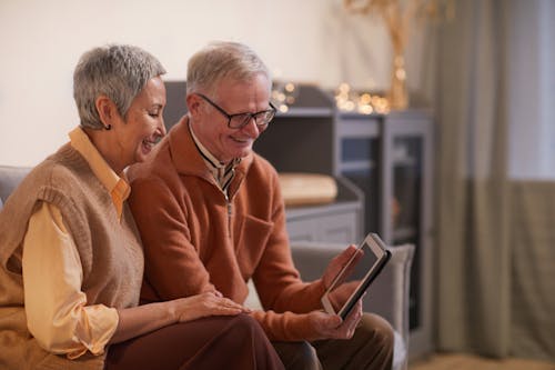 Free Couple Smiling While Looking at a Tablet Computer Stock Photo