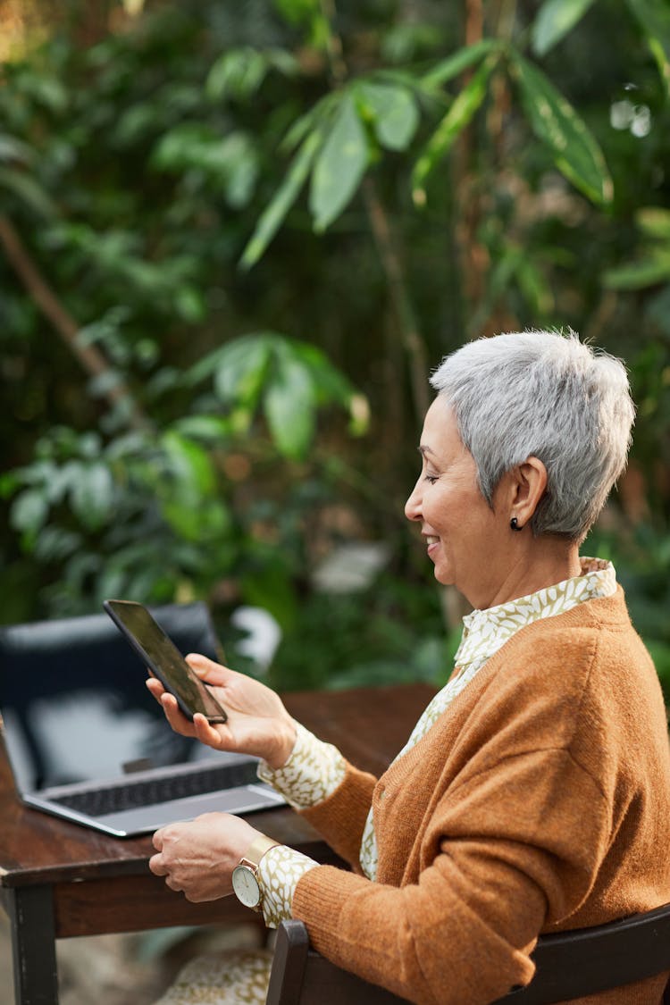 Woman Smiling While Looking At Her Smartphone