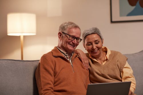 Free Man and Woman Sitting on Sofa While Looking at a Laptop Stock Photo