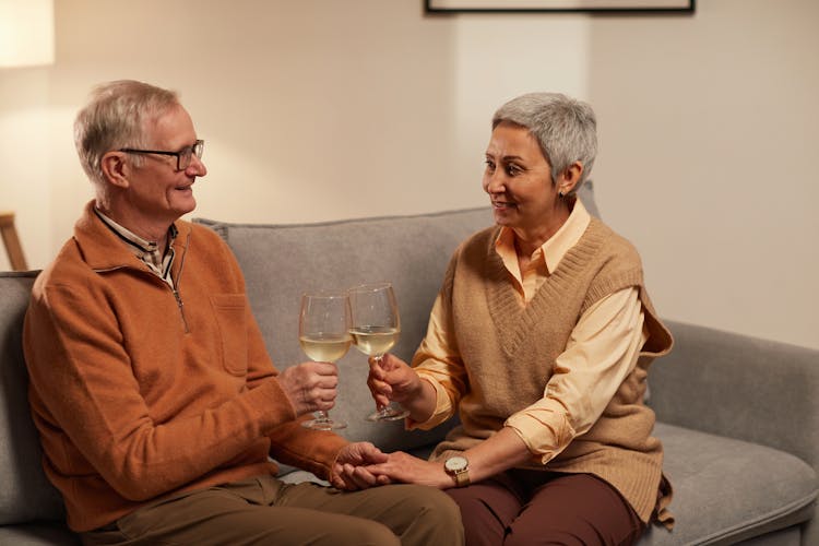 Couple Holding Each Other's Hands While Holding A Wine Glasses