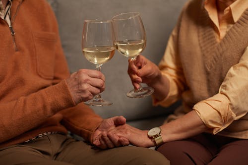 Free Couple Holding Each Other's Hands While Holding a Wine Glasses Stock Photo
