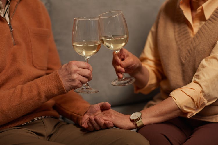 Couple Holding Each Other's Hands While Holding A Wine Glasses