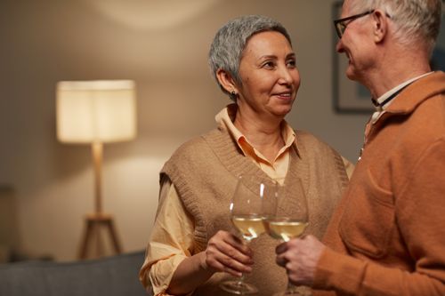 Free A senior couple sharing a tender moment with wine glasses in a cozy living room setting. Stock Photo