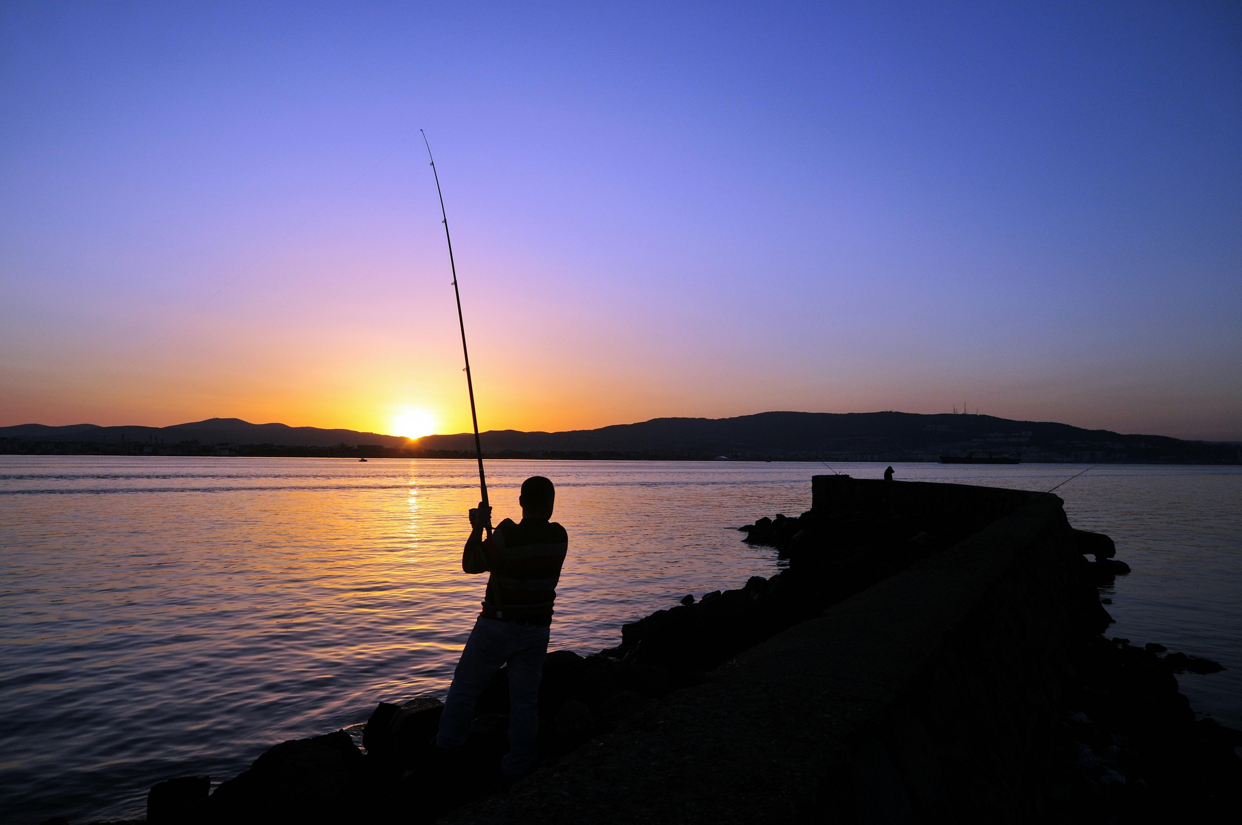 Premium Photo  Teen boy fishing with fishing rod on beach at sunset