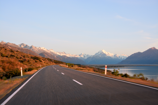 A picturesque road leading through snowy mountains and beautiful scenery, capturing the essence of New Zealand.