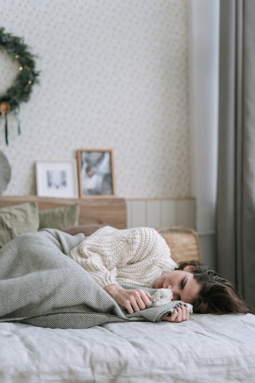 Free A Woman in White Knitted Sweater Lying on the Bed Stock Photo