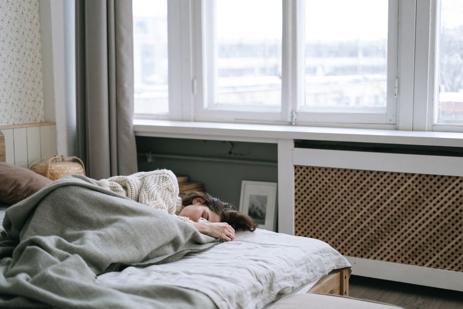Woman peacefully sleeping in a cozy bedroom with soft light and warm blankets.