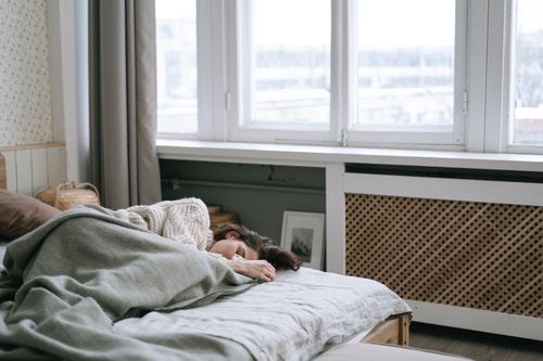 Free Woman peacefully sleeping in a cozy bedroom with soft light and warm blankets. Stock Photo