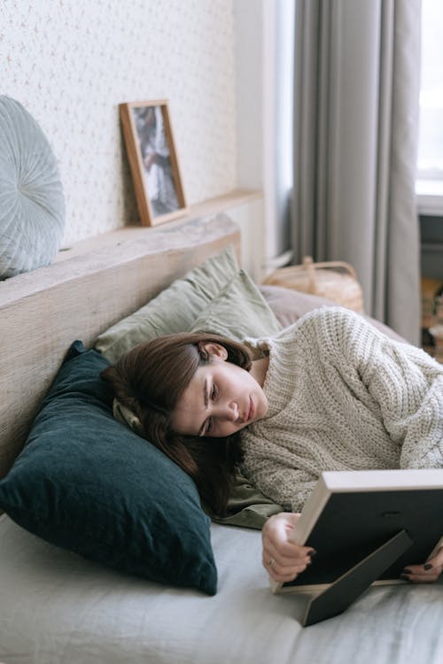 A Woman Looking at a Picture Frame While Lying Down on a Bed 