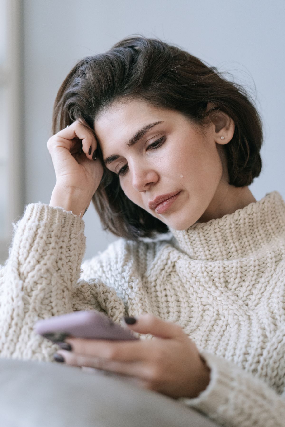 Femme qui regarde son téléphone, le message reste sans réponse