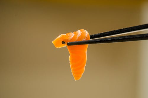 Close-Up Shot of a Person Holding a Sushi Using Chopsticks