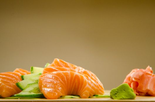 Close-up of fresh salmon sashimi with cucumber, wasabi, and ginger.