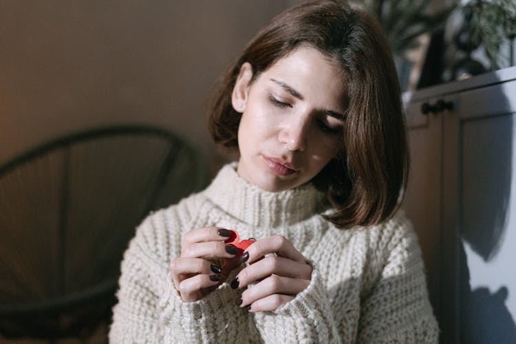 A Woman Wearing Cream Sweater Holding A Heart Paper Cut Out