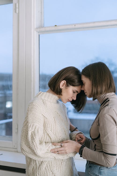 Free Women Comforting Each Other Near the Glass Window Stock Photo