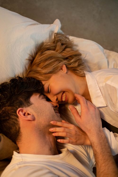 Free A loving couple lying down, sharing an intimate and joyful moment indoors. Stock Photo