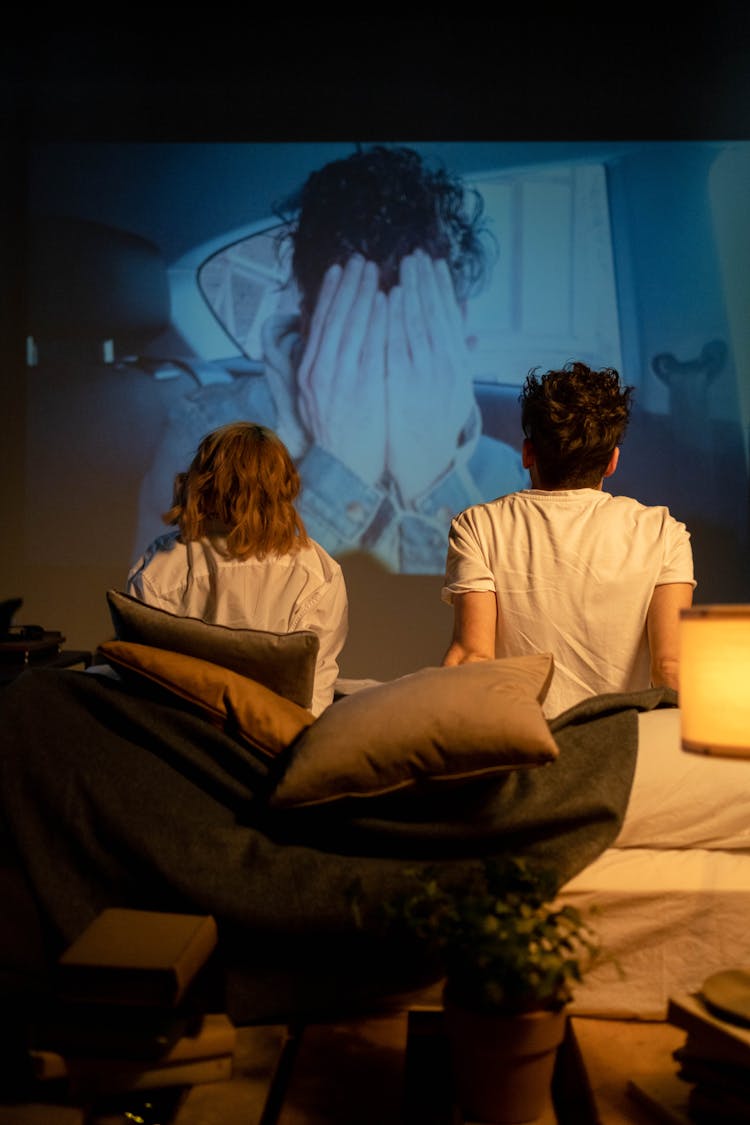 A Romantic Couple Sitting On The Bed While Watching