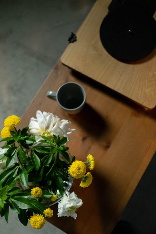 Free Aesthetic composition featuring flowers and a coffee mug on a wooden table viewed from above. Stock Photo