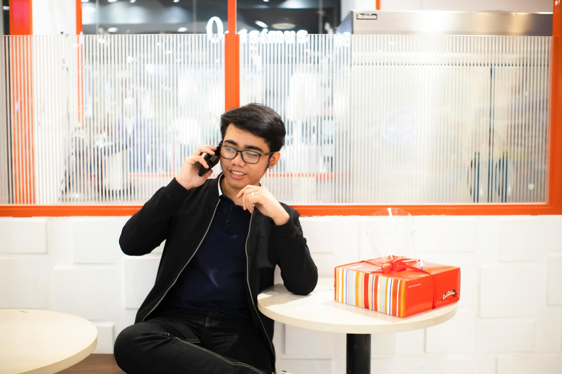 Asian man speaking on smartphone near table with gift box