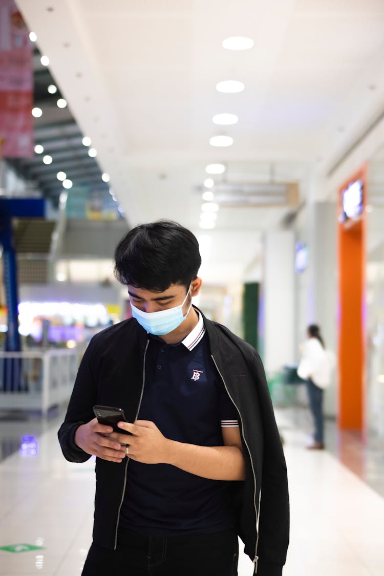 Male In Mask Using Phone In Mall