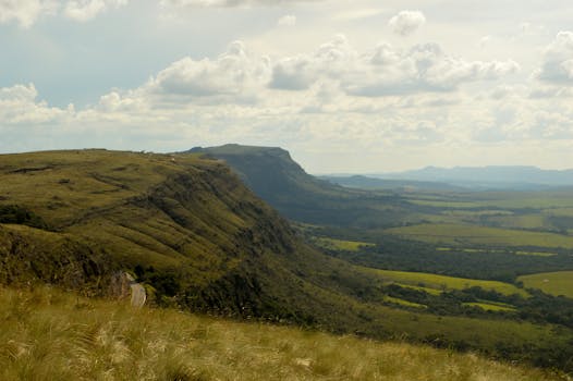 Breathtaking view of highlands and valleys with lush greenery and a distant horizon under a cloudy sky.