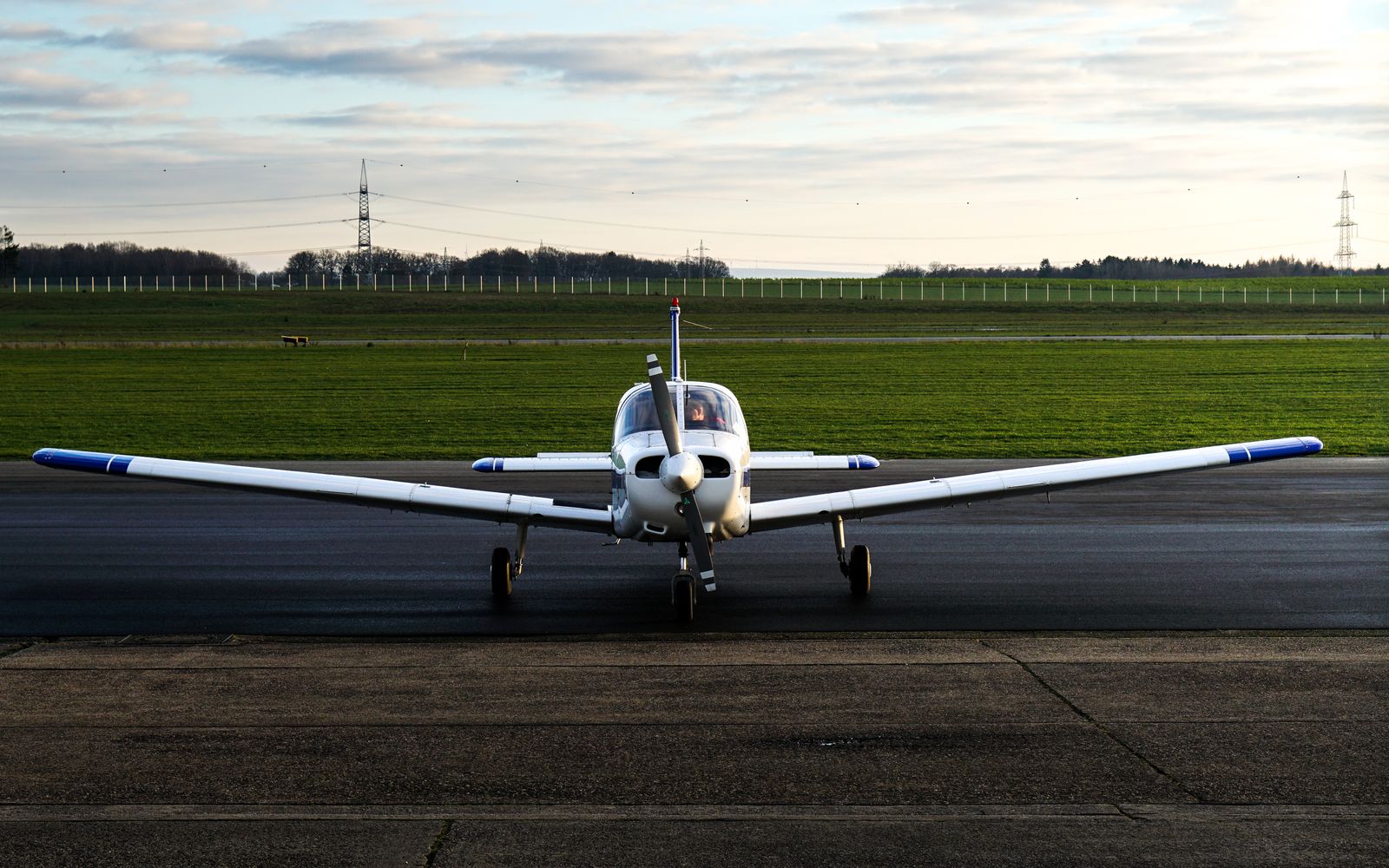 A small propeller airplane parked on a general aviation runway at sunset
