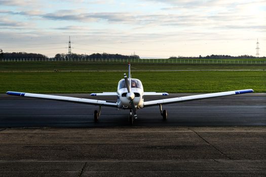 A small propeller airplane parked on an outdoor runway at sunset.