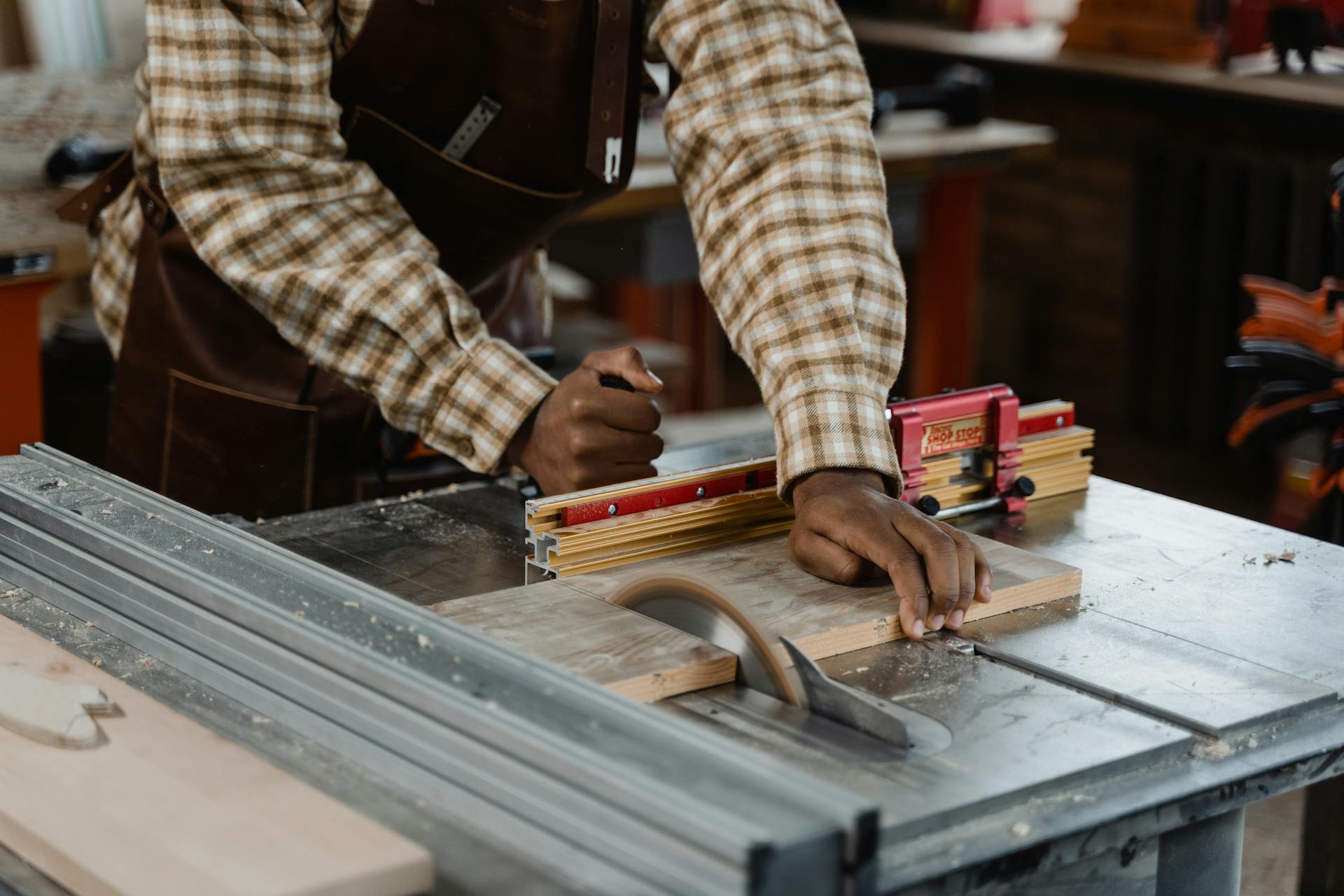 Focused artisan using a table saw, showcasing woodworking skills in a workshop.