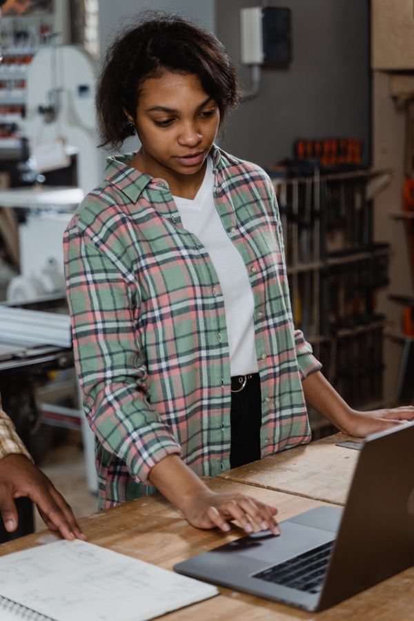 Maker at a workbench checking orders on a laptop — photo by Tima Miroshnichenko on Pexels