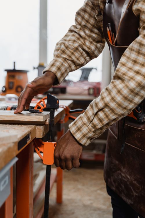 Free A craftsman focuses on woodwork using a clamp in an indoor workshop setting. Stock Photo