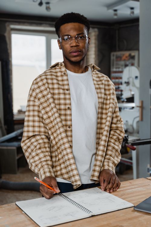 Free A focused artisan reviewing plans in a well-equipped woodworking workshop. Stock Photo