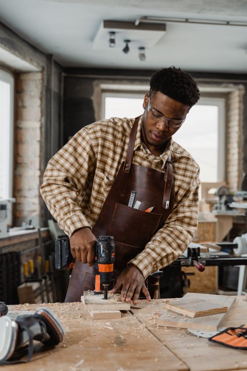 Free A craftsman focuses on woodworking using a power drill in a workshop. Stock Photo