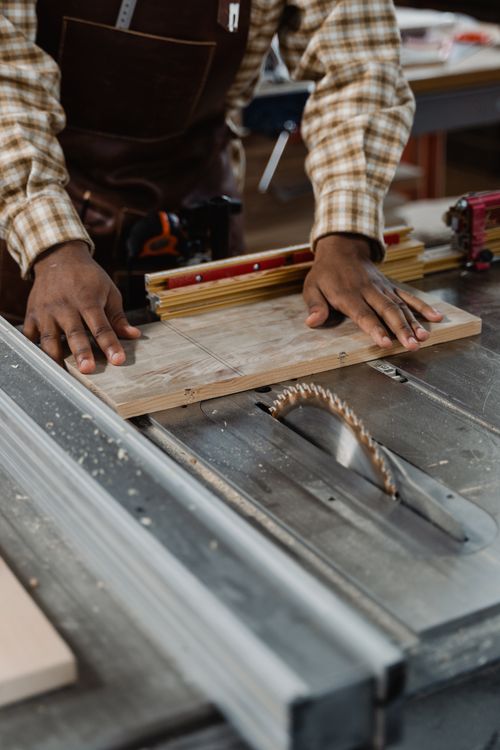 Carpenter guiding timber through a table saw
