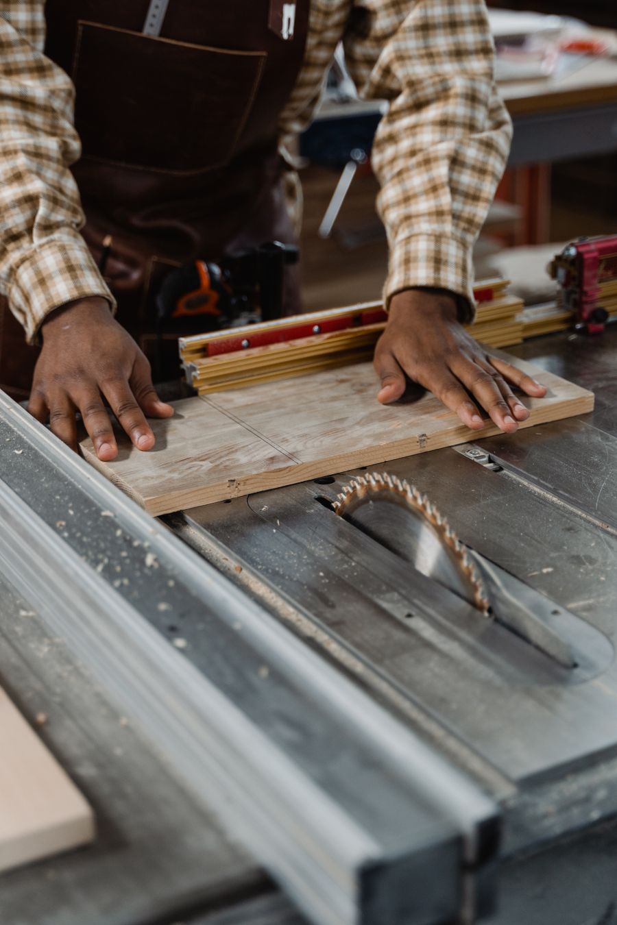 Carpenter guiding a board through a table saw with precision