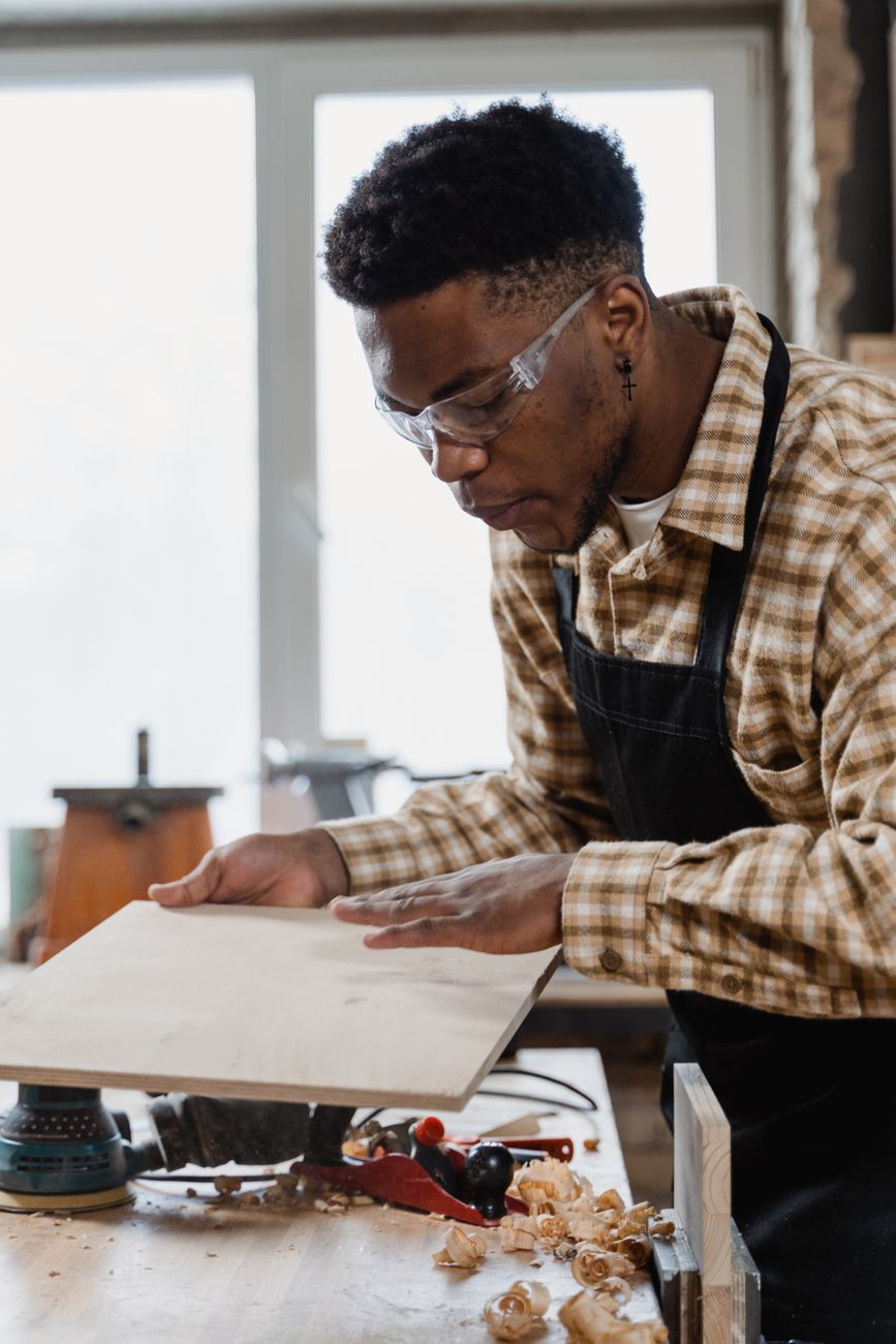 Focused craftsman smoothing a wooden board in a workshop.