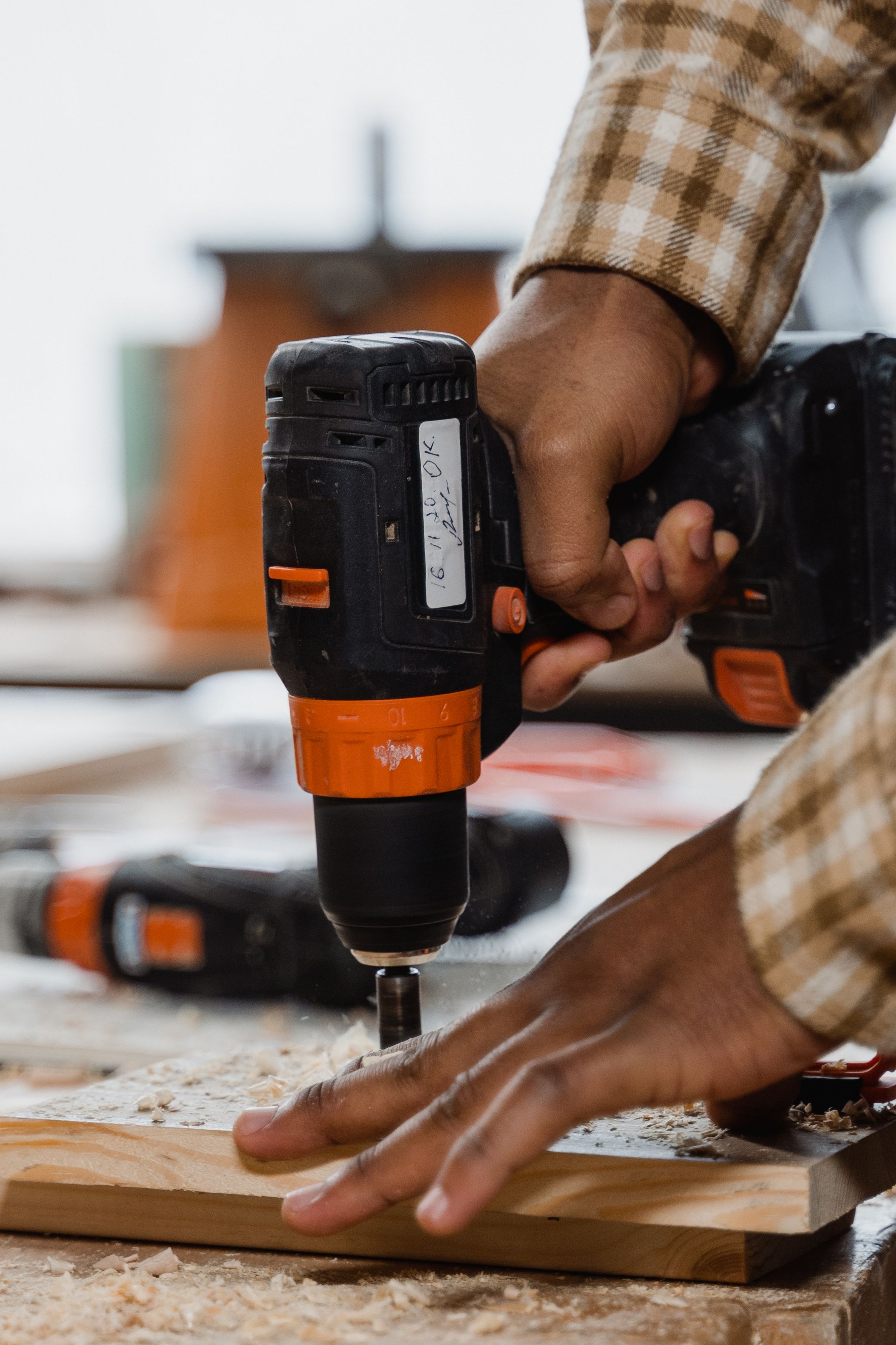 Woodworker using a cordless drill on timber during an active workshop project