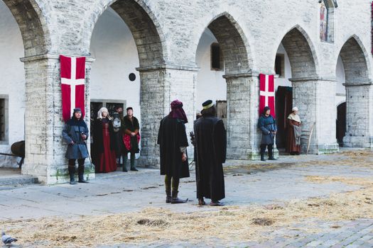 Historic stone arches setting with people in medieval costumes during a reenactment.