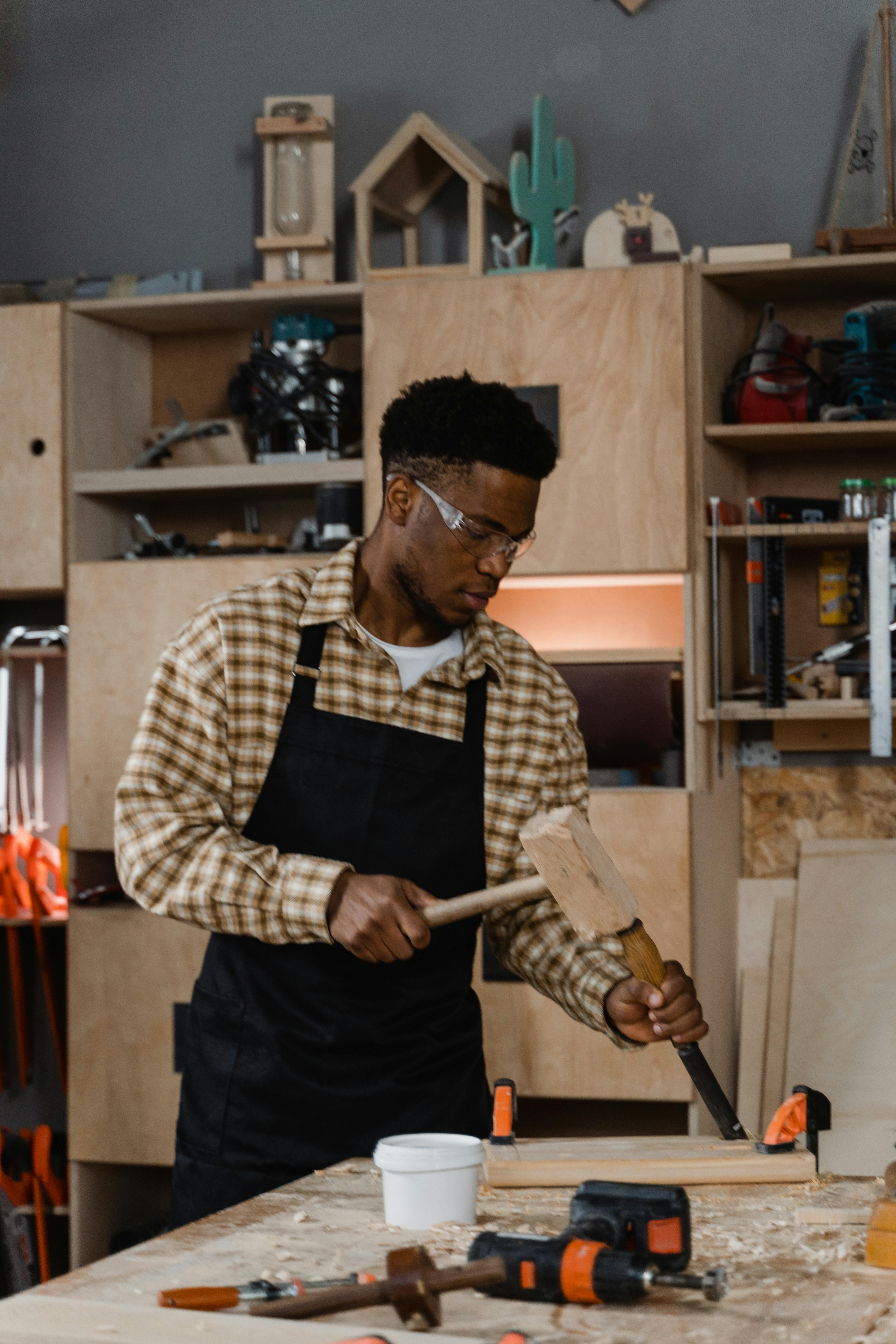 Carpenter working with tools in a well-equipped workshop, focused on woodworking.