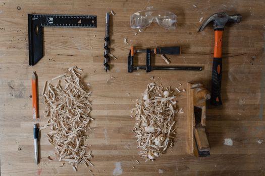 A flat lay of woodworking tools with sawdust on a wooden surface, featuring copy space.